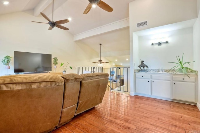 living area featuring light wood finished floors, visible vents, ceiling fan, beamed ceiling, and high vaulted ceiling