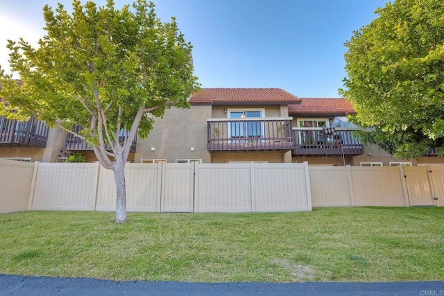 exterior space with a tile roof, fence, a lawn, and stucco siding