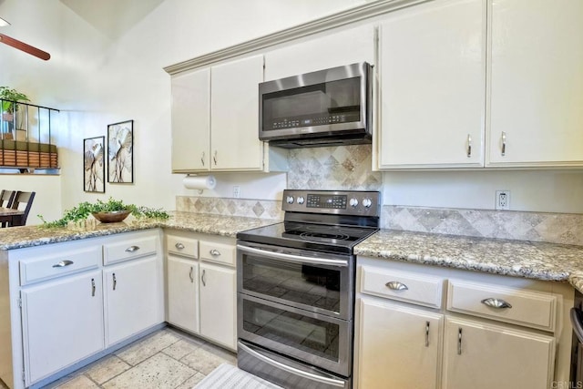 kitchen with stainless steel appliances, a peninsula, a ceiling fan, backsplash, and light stone countertops