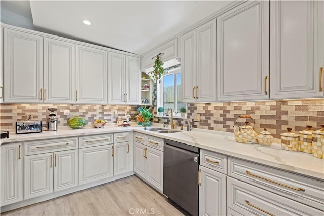 kitchen with light wood-style flooring, a sink, white cabinets, dishwasher, and tasteful backsplash