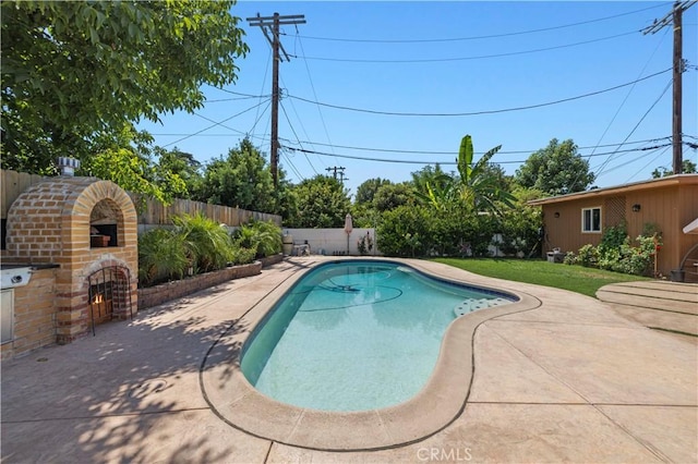 view of pool with a patio, an outdoor brick fireplace, and a fenced backyard