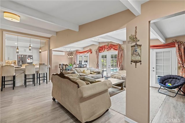 living area with lofted ceiling with beams, french doors, a wall mounted air conditioner, and light wood-style floors