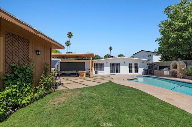 view of pool with a patio, fence, a yard, french doors, and exterior kitchen