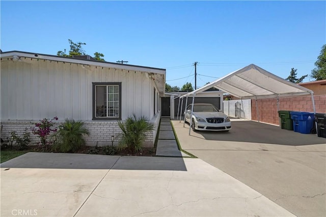 view of property exterior with driveway, fence, a carport, and brick siding