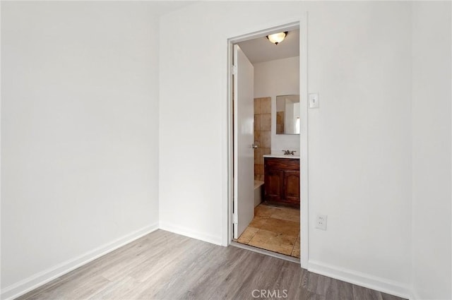 interior space featuring ensuite bathroom, baseboards, and wood finished floors