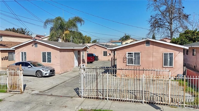 view of front of property with a fenced front yard, concrete driveway, and stucco siding