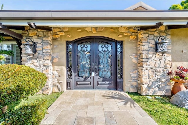 view of exterior entry with stone siding and french doors