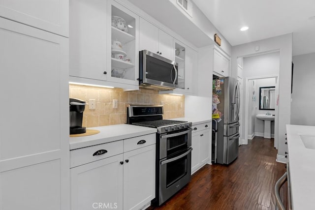 kitchen with visible vents, decorative backsplash, stainless steel appliances, light countertops, and white cabinetry