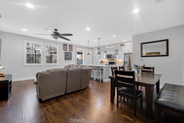 living area with baseboards, dark wood-type flooring, and recessed lighting