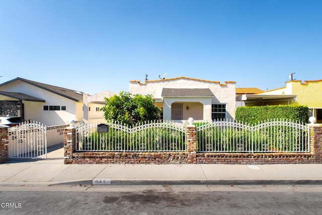 view of front of property with a fenced front yard, a gate, and stucco siding