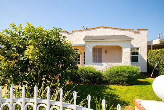 view of front of house featuring a front yard, fence, and stucco siding