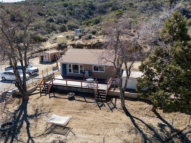 back of house featuring fence, a wooded view, and a wooden deck