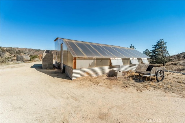 view of front of property featuring a greenhouse and an outdoor structure