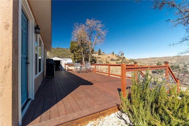 wooden deck with a mountain view and area for grilling