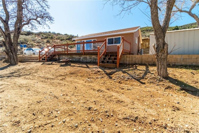 view of front of home with a deck, stairway, and fence