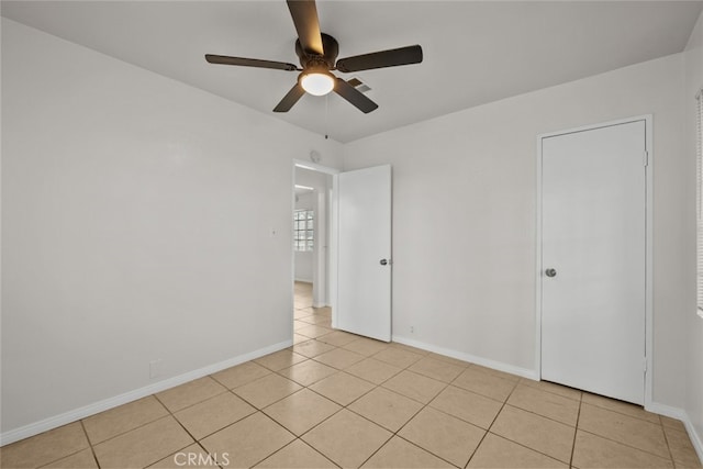 spare room with light tile patterned flooring, a ceiling fan, and baseboards