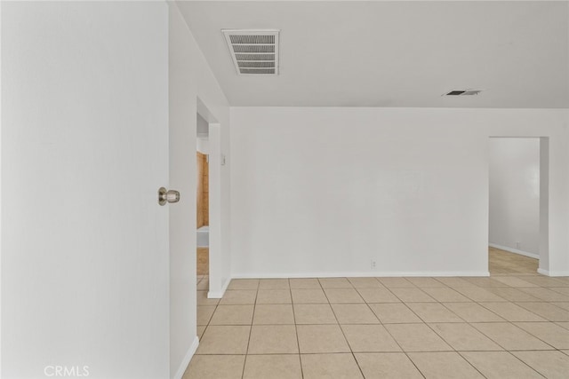 empty room with light tile patterned floors, baseboards, and visible vents