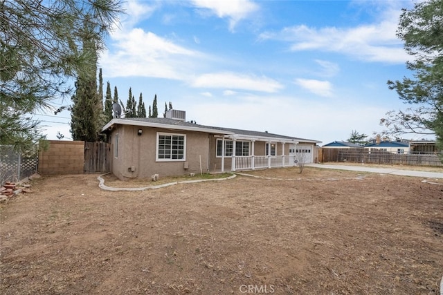 view of front of house with a garage, central AC, fence, and stucco siding