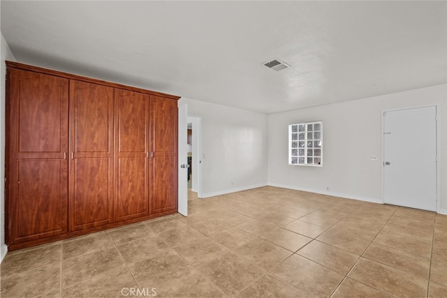 unfurnished bedroom featuring baseboards, visible vents, and light tile patterned flooring