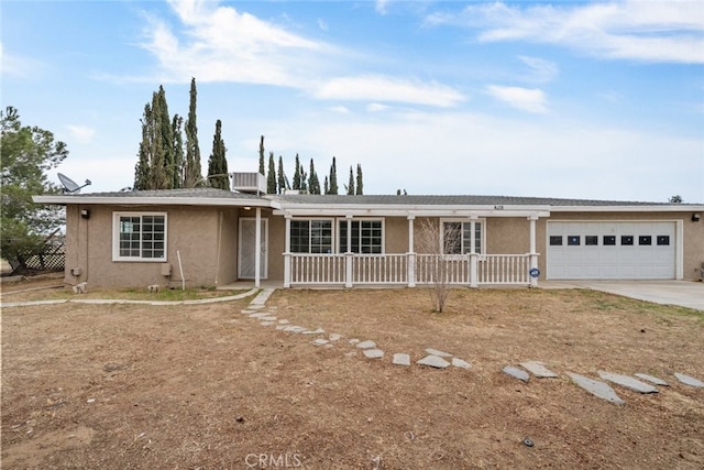 ranch-style home with a porch, an attached garage, central air condition unit, concrete driveway, and stucco siding