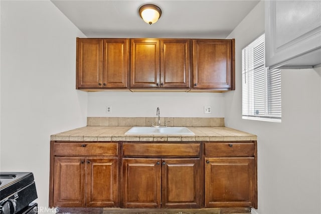 kitchen featuring brown cabinetry, range with electric cooktop, and a sink