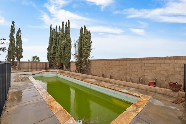 view of swimming pool with a fenced backyard, a pool with connected hot tub, and a patio