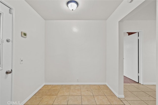 unfurnished room featuring baseboards and light tile patterned flooring