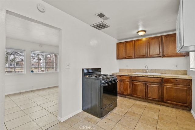 kitchen featuring visible vents, brown cabinets, a sink, and gas stove