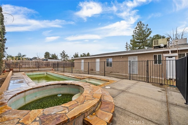 view of pool with fence and an in ground hot tub