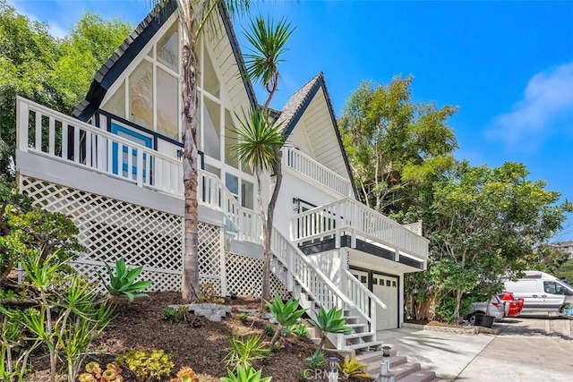 view of side of home featuring a garage, concrete driveway, and stairway