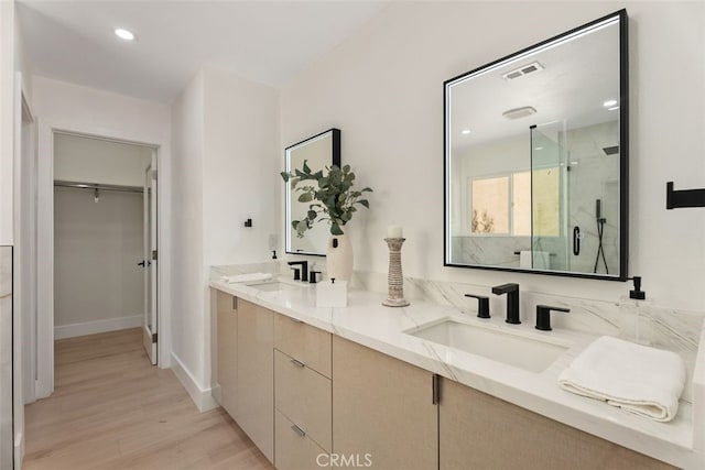 full bath with a stall shower, visible vents, a sink, and wood finished floors