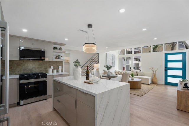 kitchen with tasteful backsplash, stainless steel microwave, visible vents, modern cabinets, and gas range