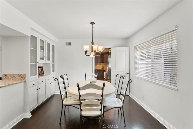 dining area with dark wood-style floors, baseboards, visible vents, and an inviting chandelier