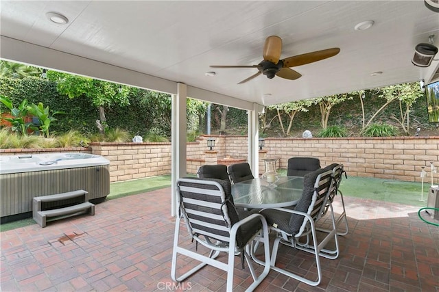 view of patio / terrace with outdoor dining area, a ceiling fan, and a hot tub