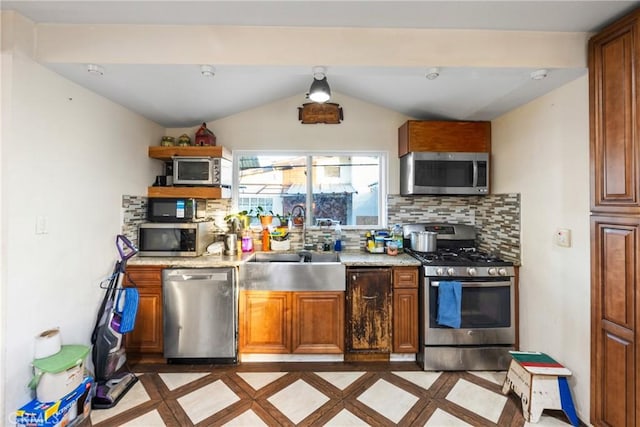 kitchen featuring stainless steel appliances, a sink, vaulted ceiling, tasteful backsplash, and brown cabinetry