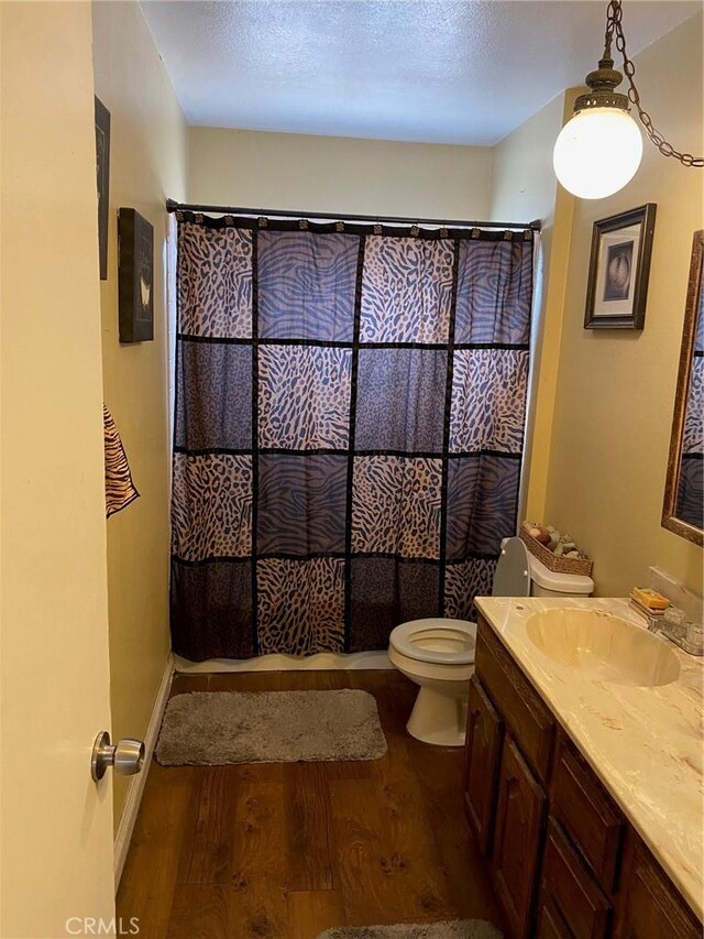 3158 E E Ave H8, Lancaster, CA 93535 - full bath with wood finished floors, toilet, vanity, a textured ceiling, and a shower with shower curtain