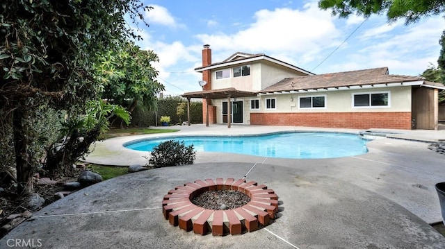 outdoor pool with a patio area and a fire pit