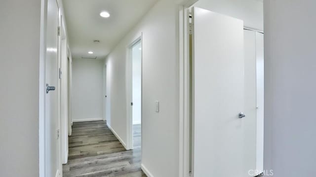 hall featuring light wood-type flooring, baseboards, and recessed lighting