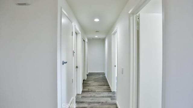 corridor featuring baseboards, wood finished floors, and recessed lighting