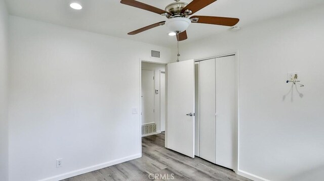 unfurnished bedroom with baseboards, visible vents, a ceiling fan, light wood-style floors, and a closet