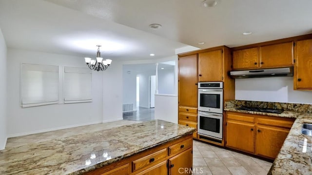 kitchen featuring under cabinet range hood, double oven, brown cabinets, and black gas stovetop