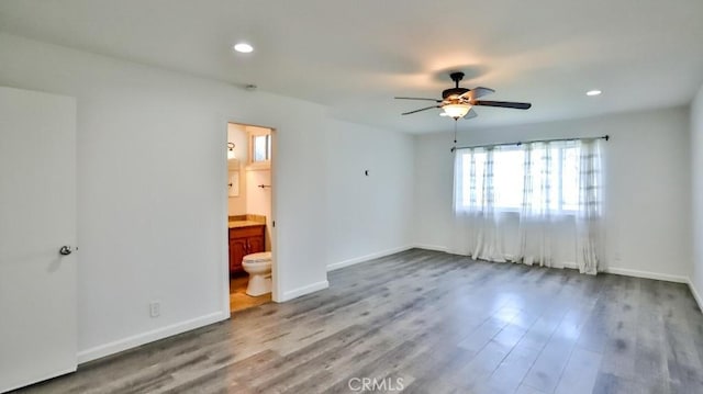 unfurnished bedroom featuring recessed lighting, ceiling fan, ensuite bath, wood finished floors, and baseboards