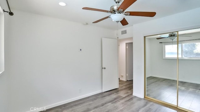 unfurnished bedroom featuring recessed lighting, wood finished floors, visible vents, baseboards, and a closet