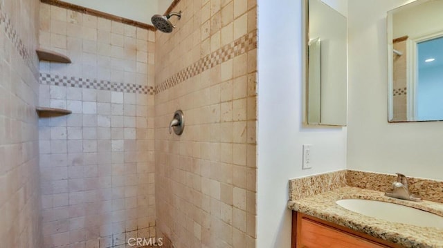 full bath with tiled shower and vanity