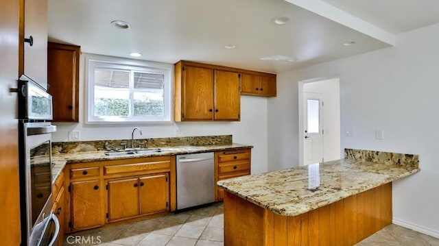 kitchen with light stone counters, a peninsula, a sink, stainless steel dishwasher, and brown cabinetry