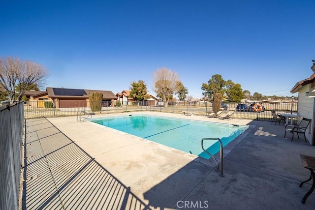 community pool with a patio and fence