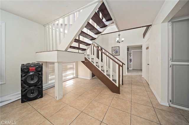 stairway featuring baseboards, tile patterned flooring, and a notable chandelier