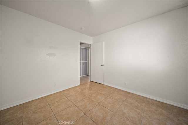 unfurnished room with light tile patterned floors and baseboards