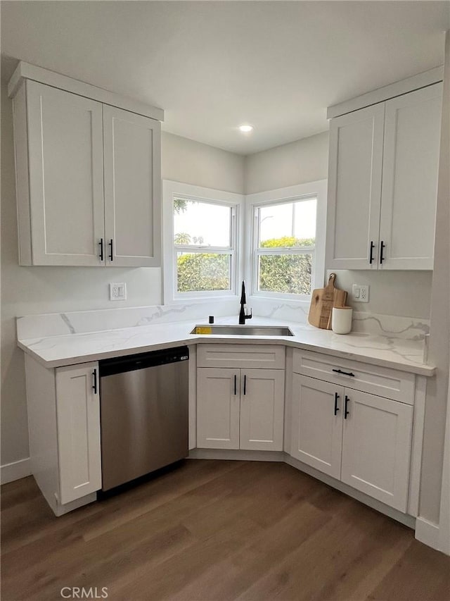 kitchen with wood finished floors, stainless steel dishwasher, a sink, and white cabinetry