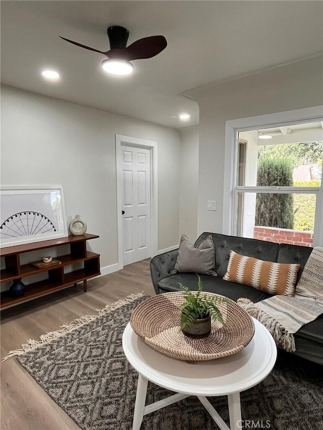 living room featuring ceiling fan, wood finished floors, and baseboards